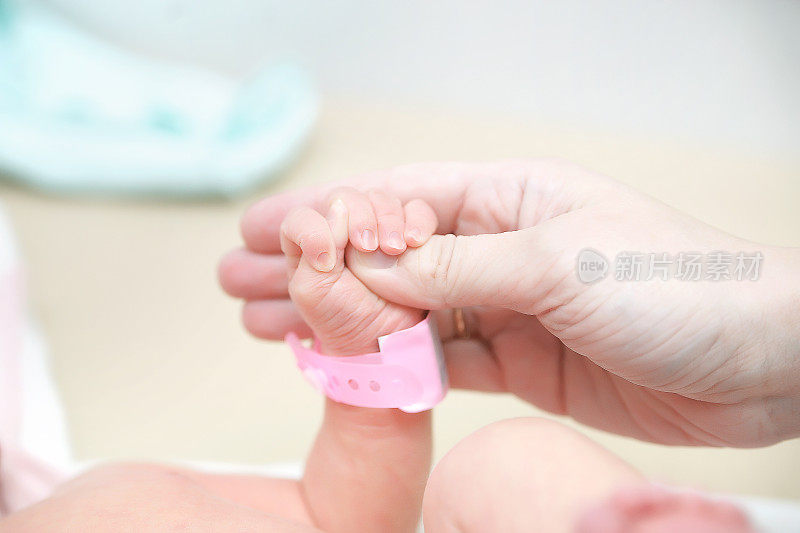 妈妈小心地握着小婴儿的把手，婴儿睡着了，小手指放在小把手上。