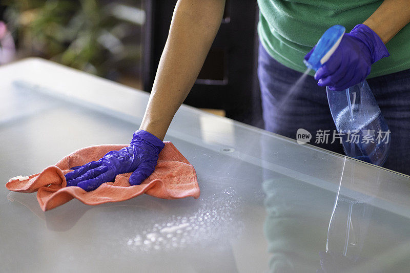 表消毒。清洁表面。女士戴着手套和消毒剂擦拭桌子，以防止细菌和细菌感染