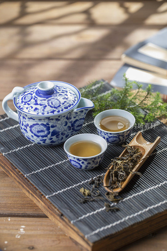光影下的青花瓷中国茶壶和茶杯在竹简上