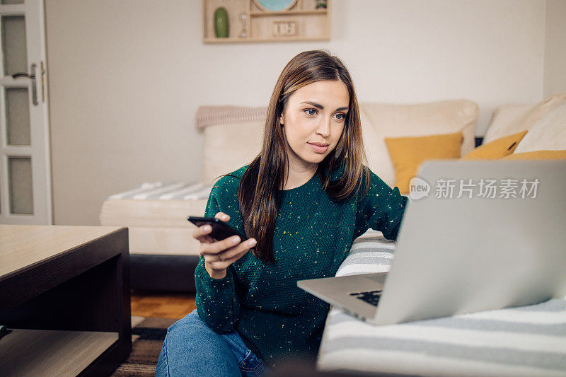 一个年轻的女商人用电话和网上工作的肖像