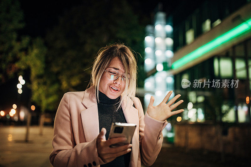现代女性晚上在城市的街道上使用电话