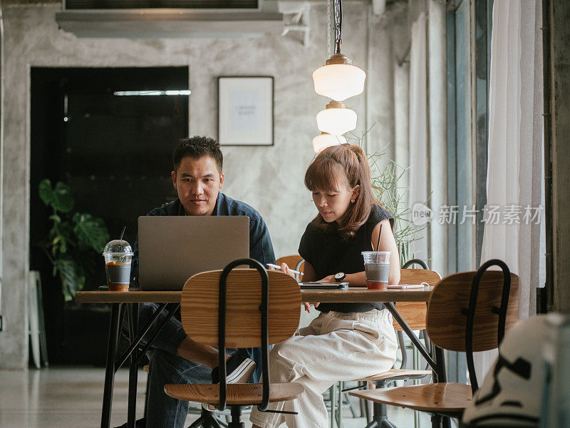 一对亚洲夫妇在咖啡馆谈生意。