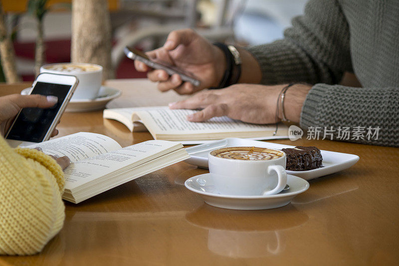 情侣们在咖啡馆里一边看书，一边喝咖啡。