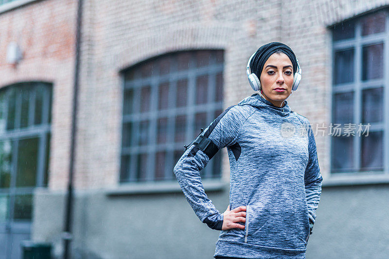 坚定的穆斯林女运动员戴着耳机在户外
