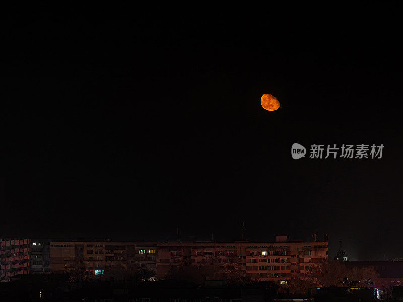 一轮橙色的大月亮低低地挂在多层住宅楼上。夜景，沉睡的城市。天文学，地球月食卫星。月在万宁长臂猿相。月光在瓦尔纳。夜景。
