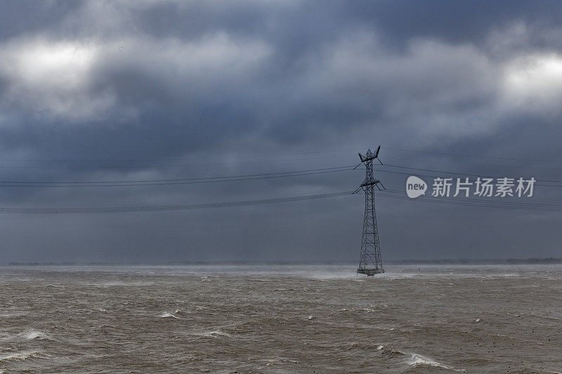 海上电力塔在暴风雨中与大浪袭击海岸