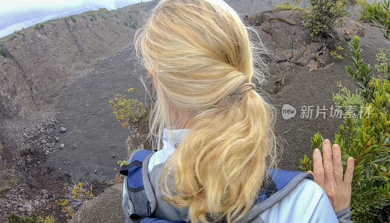 一名女子沿着火山边缘徒步旅行