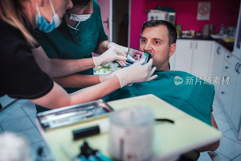 牙医和护士通过智能手机拍摄病人的牙齿