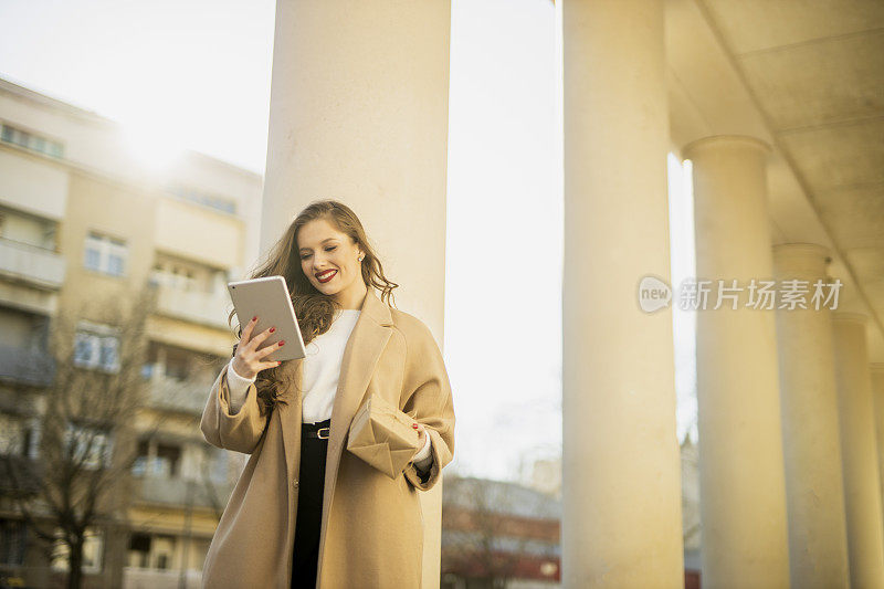 女人拿着礼盒，在户外使用她的数码平板电脑