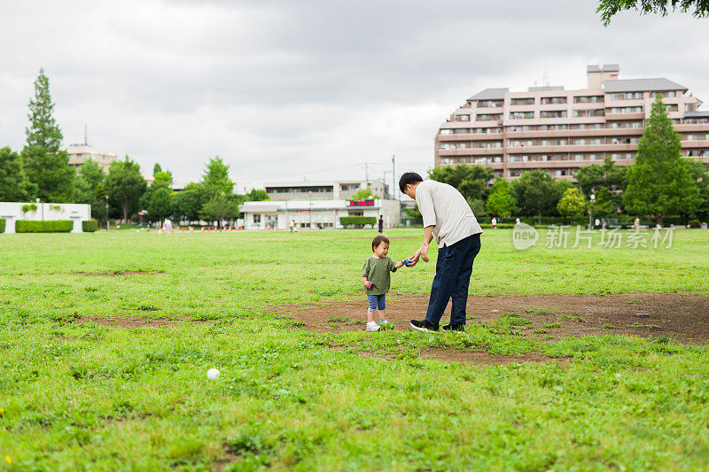 一个日本小男孩和他年轻的父亲在公园里玩耍