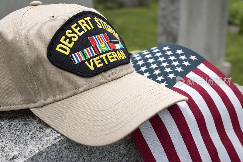 沙漠风暴老兵在墓地的美国国旗墓碑前戴上帽子