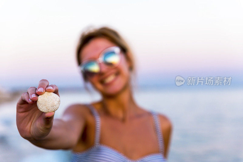 一个女人在海滩上拿着白色的石头