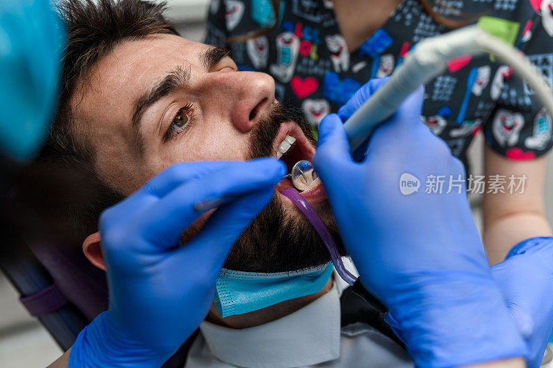 一个年轻人坐在牙科椅上，正在治疗他的牙齿。特写镜头。