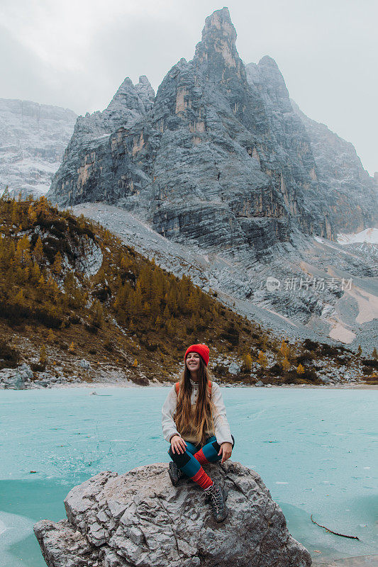 快乐的女旅行者坐在岩石上享受风景的tuquouise冻结高山湖在阿尔卑斯山