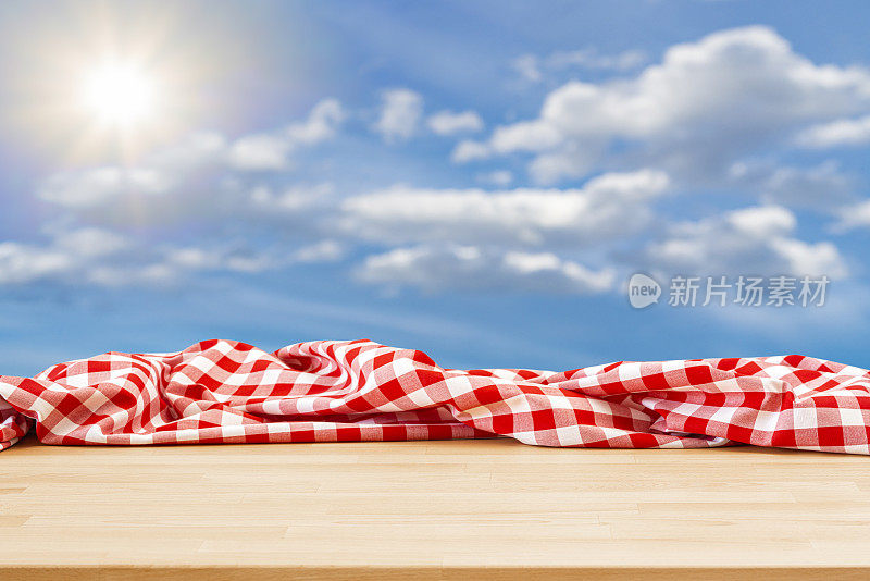 空荡荡的餐桌上铺着皱巴巴的野餐毯子，天空湛蓝