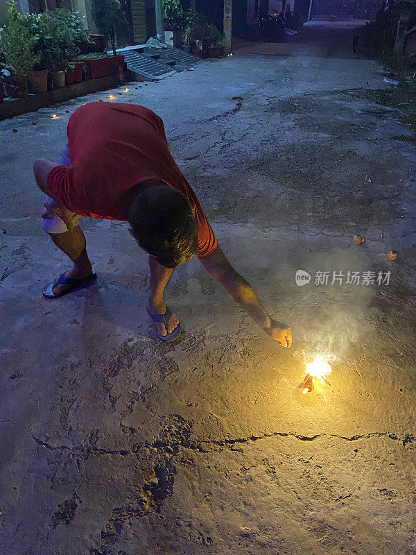 印度男子手持点燃的朋克(冒烟的棍子)，弯腰点燃喷泉烟花，这是印度传统的灯节，排灯节