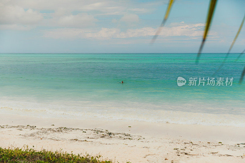 男性在热带岛屿上享受假期，在绿松石海洋中游泳