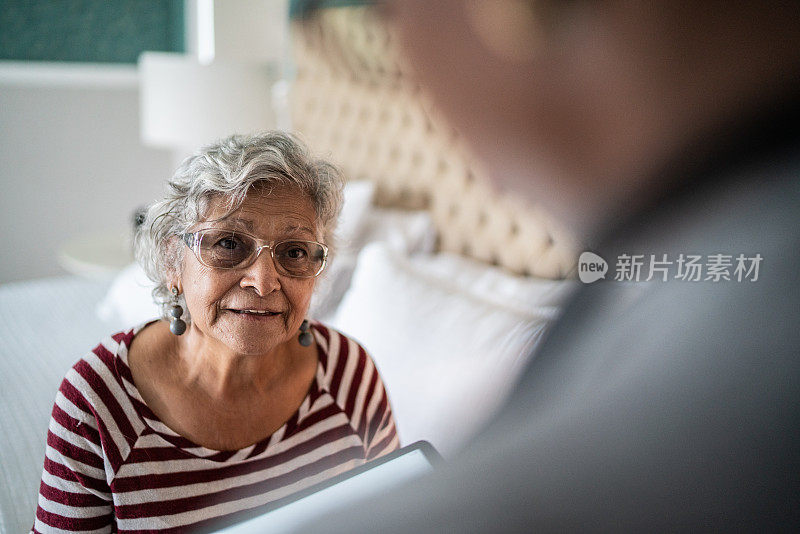 医生在卧室里和一位年长的女性聊天