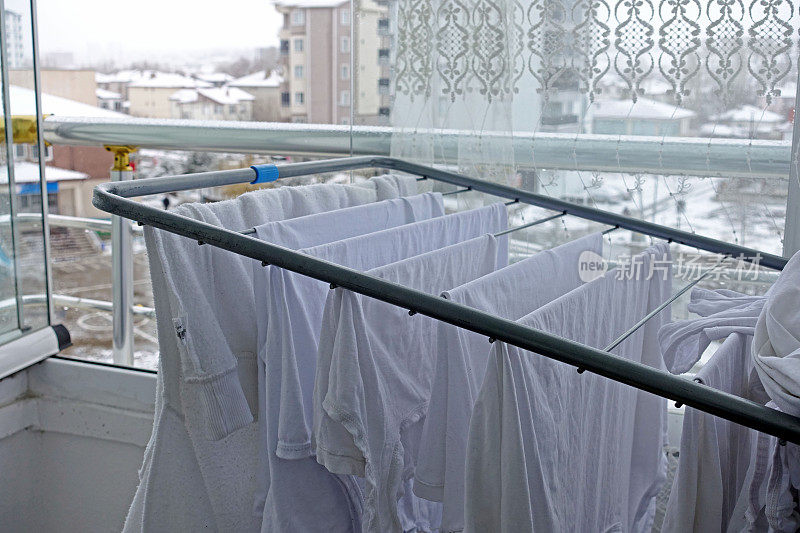 冬天在阳台晒衣服，白色的衣服晾在衣架上，晒阳台和衣服，