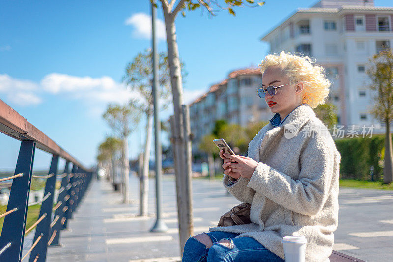 震惊的年轻女子的肖像看着智能手机的屏幕，带着悲伤的表情