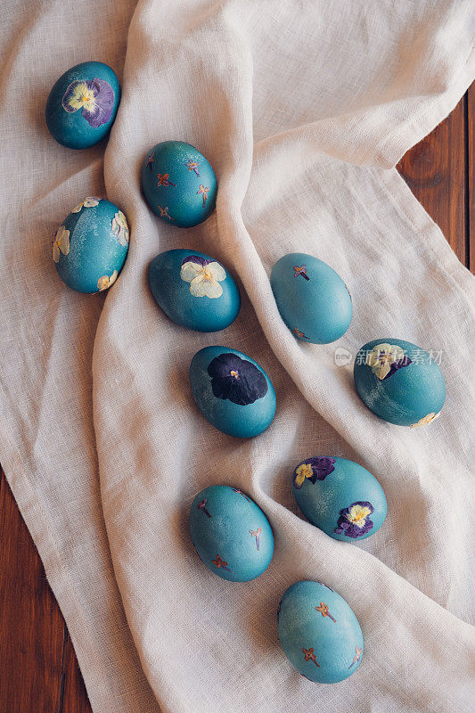 自然染色的青蓝压花复活节蛋在中性米色桌布背景，俯视图。手工工艺，天然装饰。