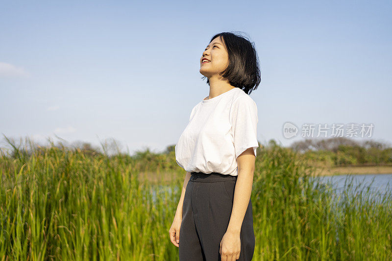 一位亚洲妇女在美丽的湖边眺望远方