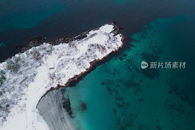 在挪威的冬季日落期间，鸟瞰风景如画的turqouse海和地平线上的雪山