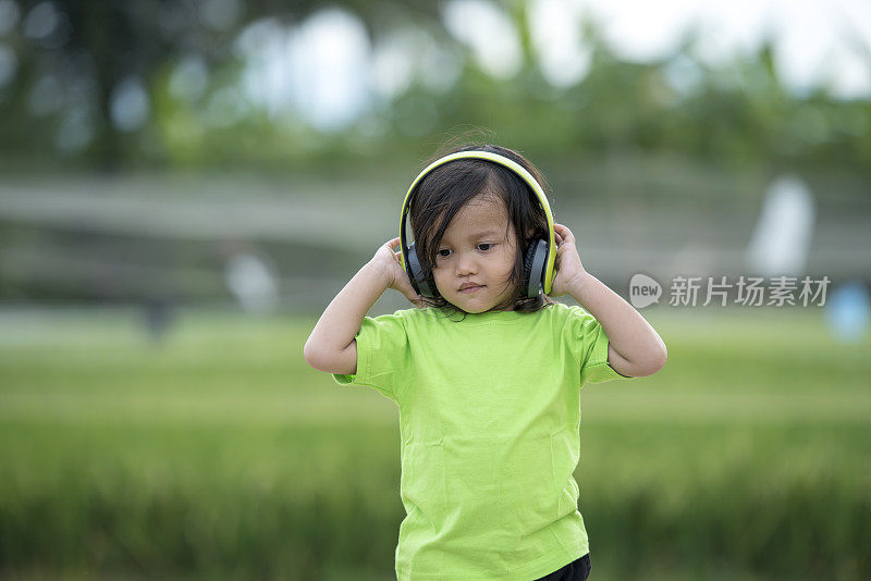 蹒跚学步的男孩用耳机听音乐