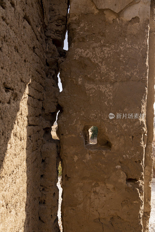 风化的泥砖废墟上的缝隙让人瞥见墙外的农村地区