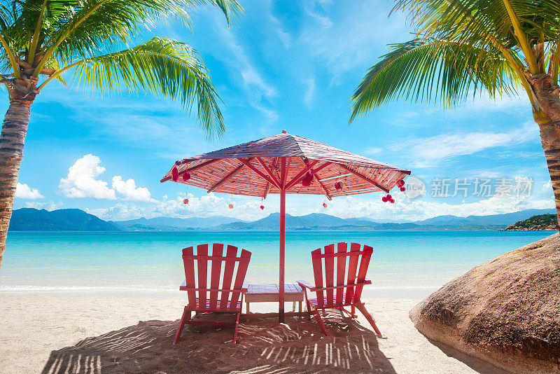 夏天，在热带海滩的躺椅上，撑着粉红色的伞放松身心。度假海滩暑假概念。