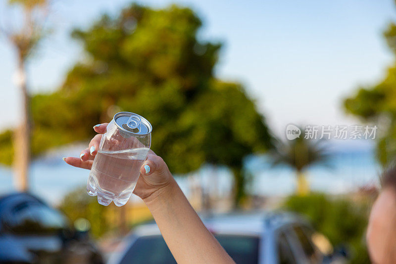 面目全非的女子拿着装着水的塑料罐，以大自然为背景