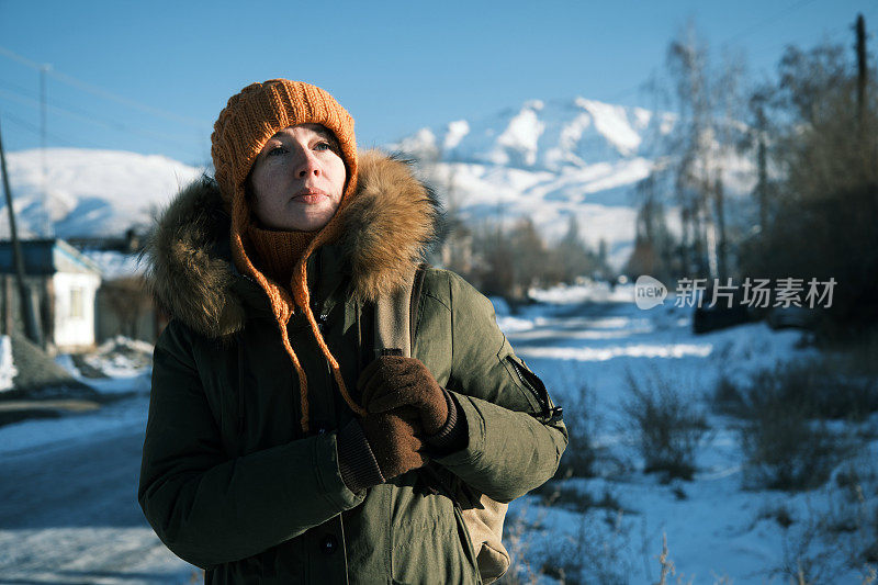 在阳光明媚的冬日小镇的街道上，女人在等人