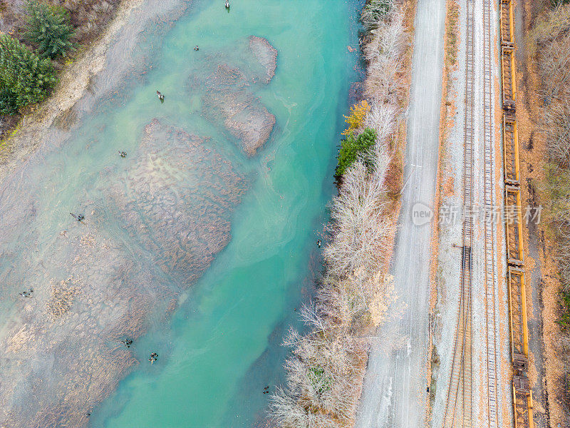 火车轨道和道路运行沿着清澈的蓝色冰川河植被Arial照片