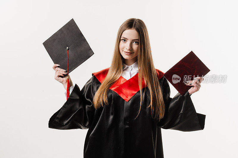 白色背景下，身着黑色毕业服的女研究生手持毕业证书和帽子。年轻迷人的女子大学毕业。