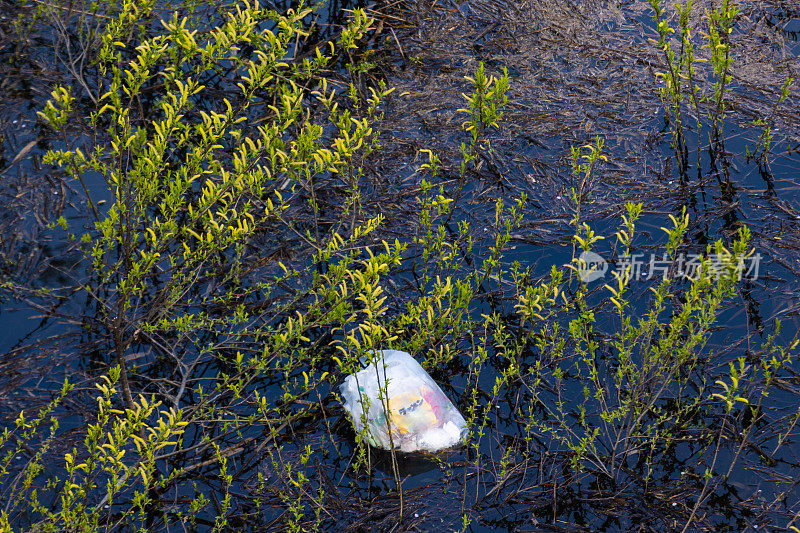 装满垃圾的垃圾袋被扔进大自然，污染了湖泊