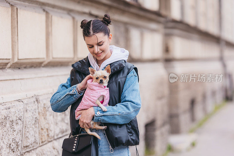 带着吉娃娃狗的年轻美女，城市背景