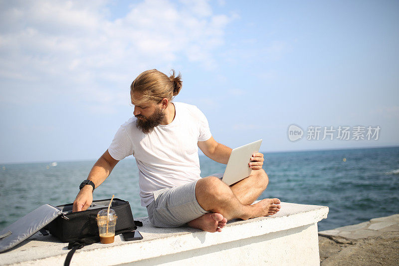 一名男子一边在海滩上放松，一边在笔记本电脑上阅读电子邮件