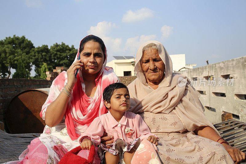 印度家庭坐在家里的沙派上，用手机聊天
