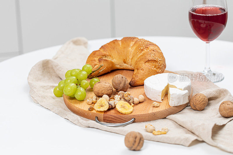 什锦奶酪，坚果，水果，羊角面包和葡萄酒。现代厨房里的奶酪拼盘