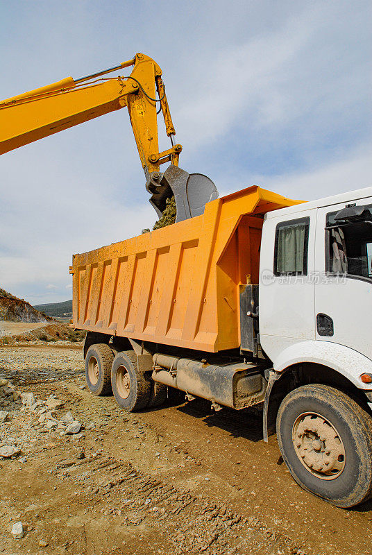 在采石场，挖掘机将岩石装载到矿用自卸卡车上。