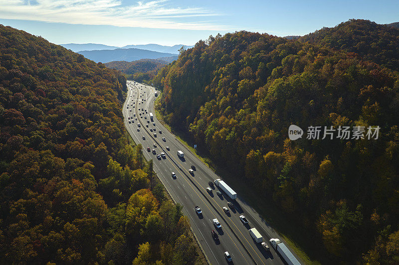 金秋时节，北卡罗莱纳州I-40高速公路穿过阿巴拉契亚山脉，通往阿什维尔，沿途行驶着快速行驶的卡车和汽车。州际运输概念