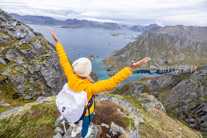 一名女子在挪威的山区徒步旅行，她张开双臂拥抱大自然