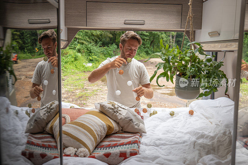一个人早上在他的露营车里整理他的床