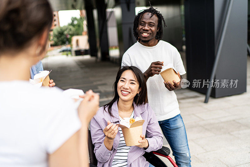 坐在轮椅上的年轻女子在户外和她的朋友们有说有笑