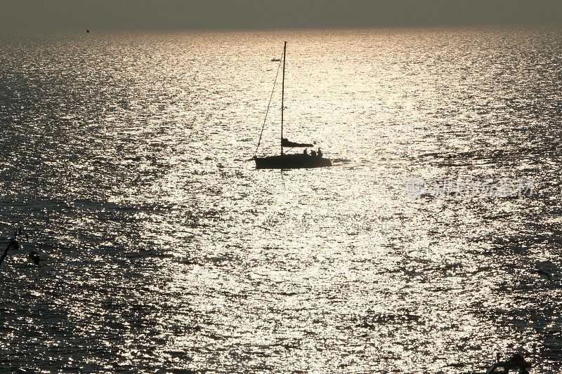 帆船在日落时随风航行。