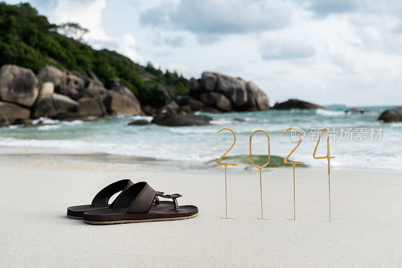 在空旷的沙滩上，以海浪和岩石为背景，为即将到来的新年写上2024