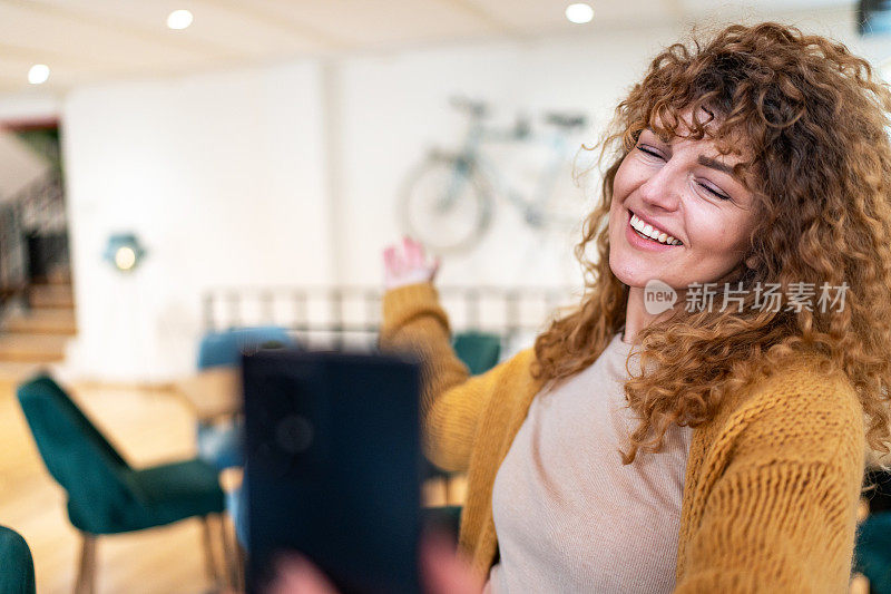 年轻女子坐在咖啡店用手机打视频电话