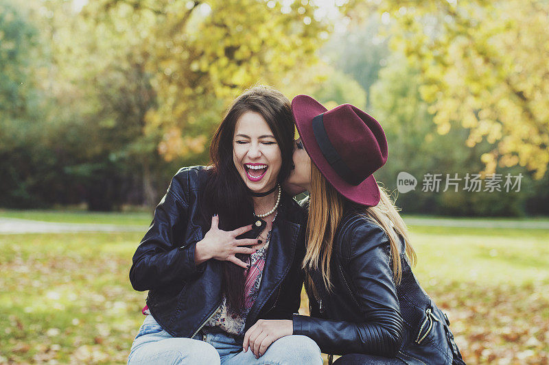 两个女孩在公园的长椅上大笑