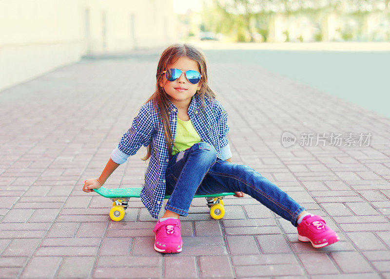 时尚小女孩坐在滑板上的城市