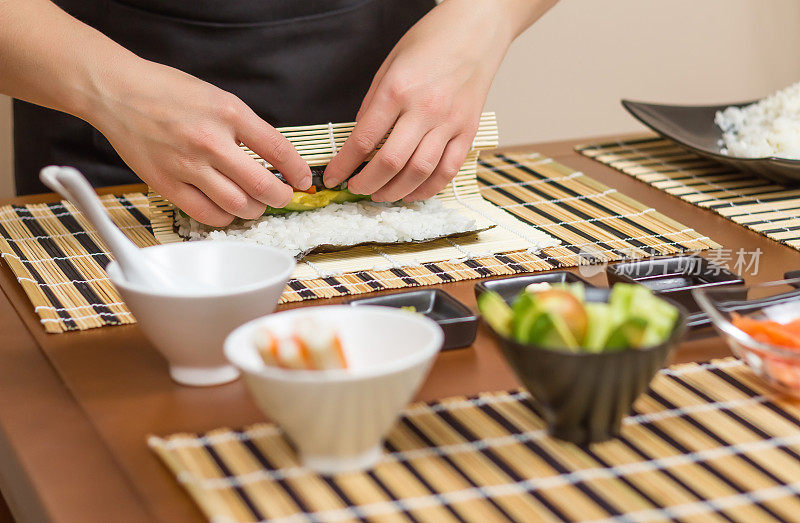 女厨师的手正在卷日本寿司